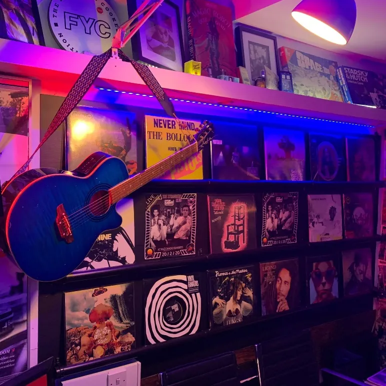 Record wall with a blue guitar at Razorhead Barbers